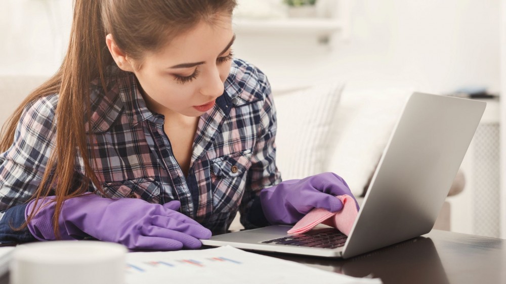 A woman cleaning a laptop keyboard.